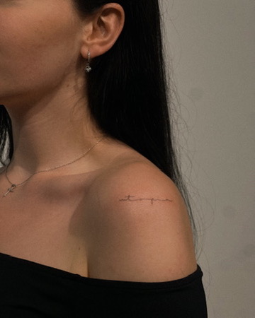Fine line script tattoo on a shoulder